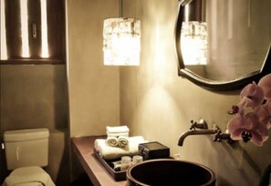Une salle de bain comprenant des toilettes, un lavabo avec un miroir, un porte-serviettes et une petite plante.