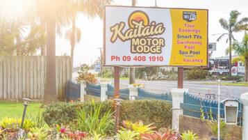 A sign for Kaitai Motor Lodge advertising amenities like tour bookings, smart TVs, a swimming pool, and a spa pool.