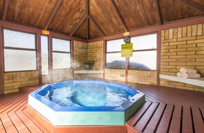 A hot tub in a wooden room with brick walls and large windows. - Kaitaia Motor Lodge (Kaitaia)