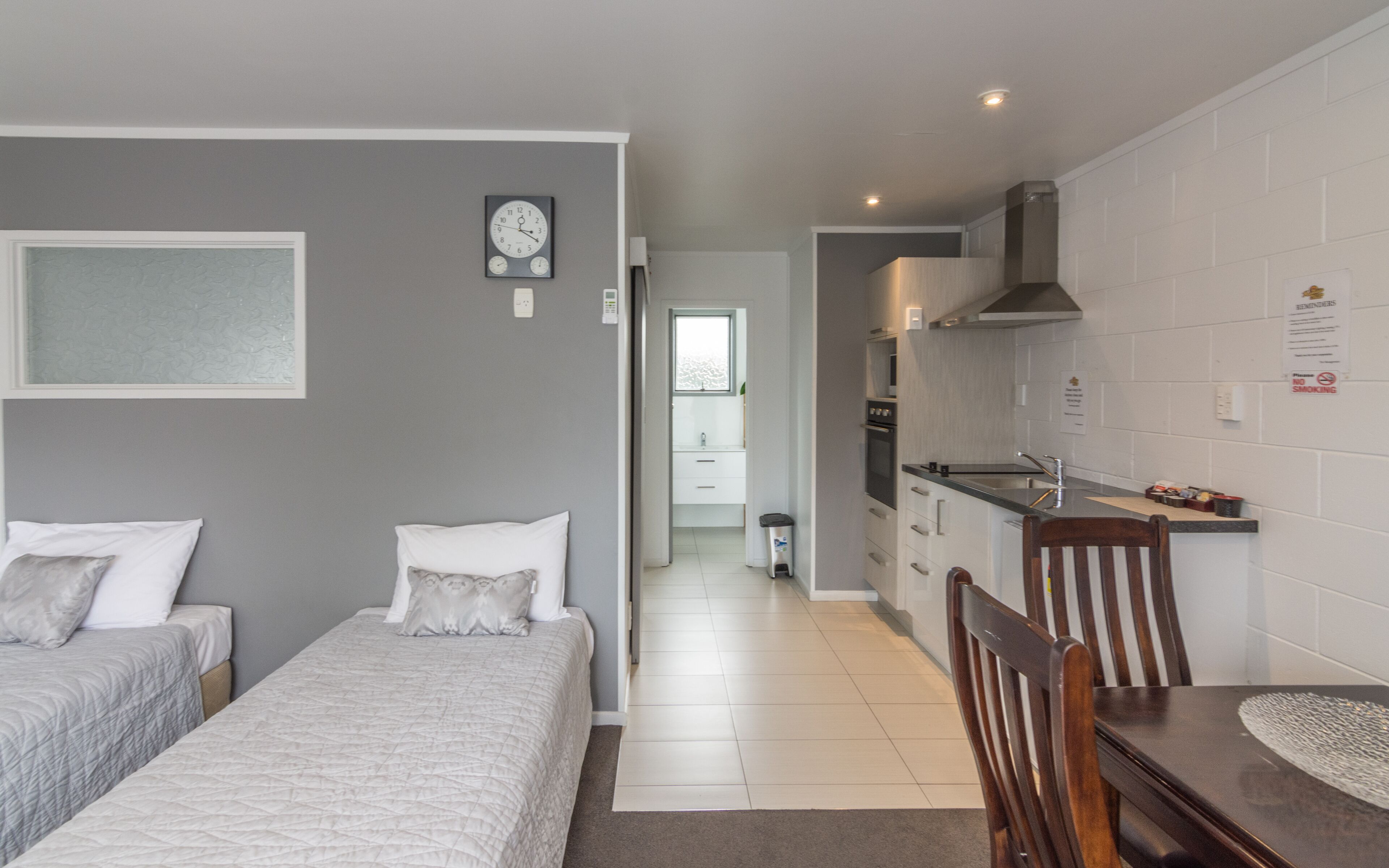 Una habitación de hotel moderna con dos camas, una kitchenette, un comedor y un baño.