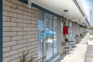 A motel with brick exterior, large windows, and outdoor seating area. - Kaitaia Motor Lodge (Kaitaia)