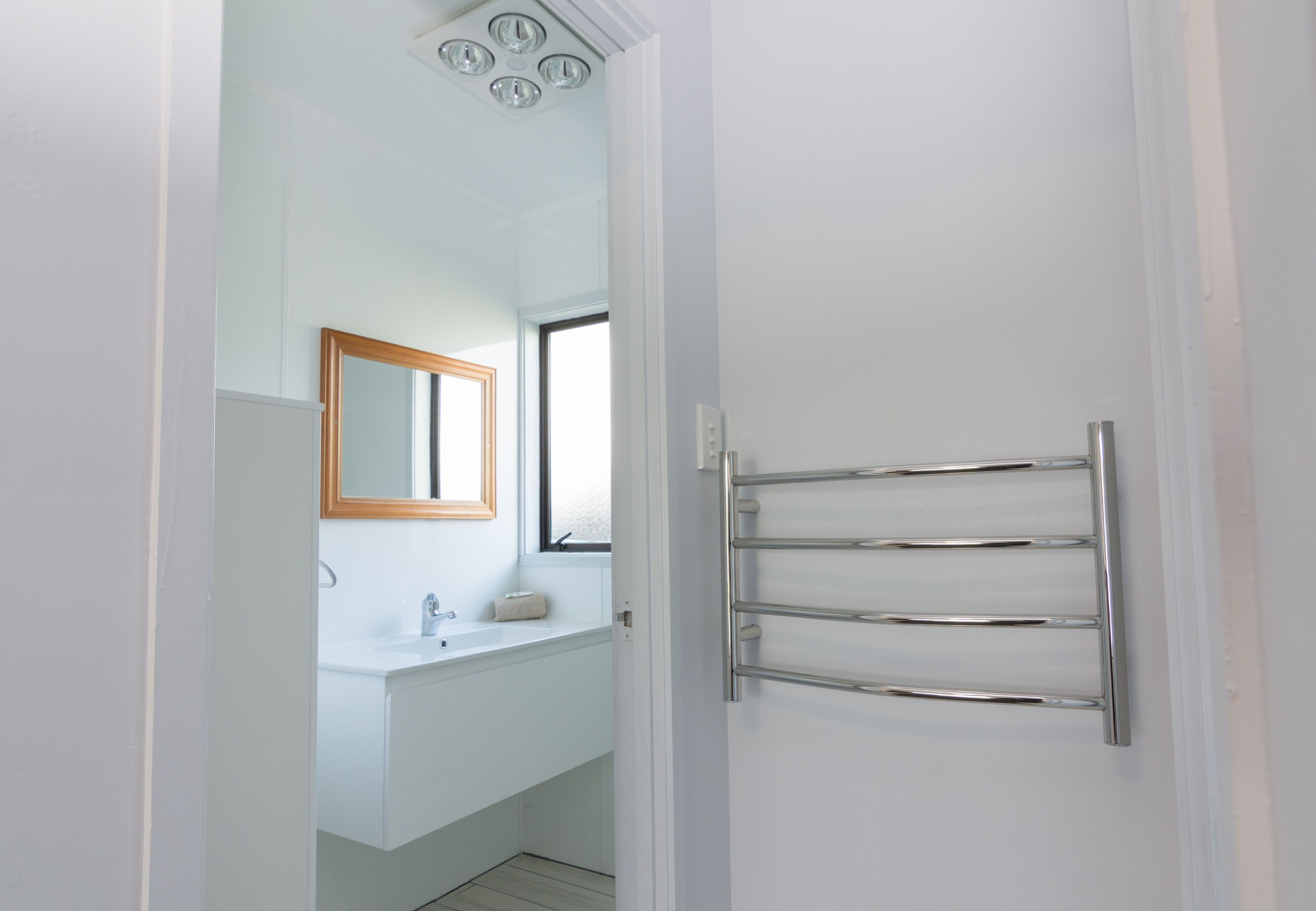 A bathroom with a white sink, a mirror, and a towel rack.