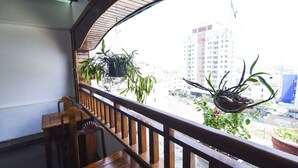Un balcon avec des balustrades en bois, une table en bois et des chaises. Des plantes en pot sont disposées sur le balcon.