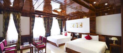 Quarto de hotel com duas camas, teto de madeira, uma mesa com cadeiras e uma lareira.