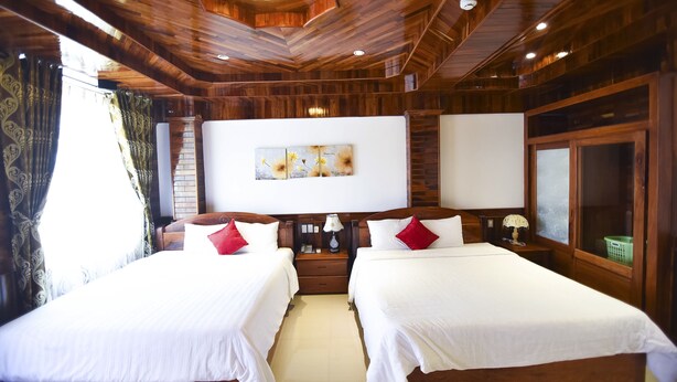 Une chambre d’hôtel avec deux lits, un plafond en bois et une grande fenêtre avec des rideaux.