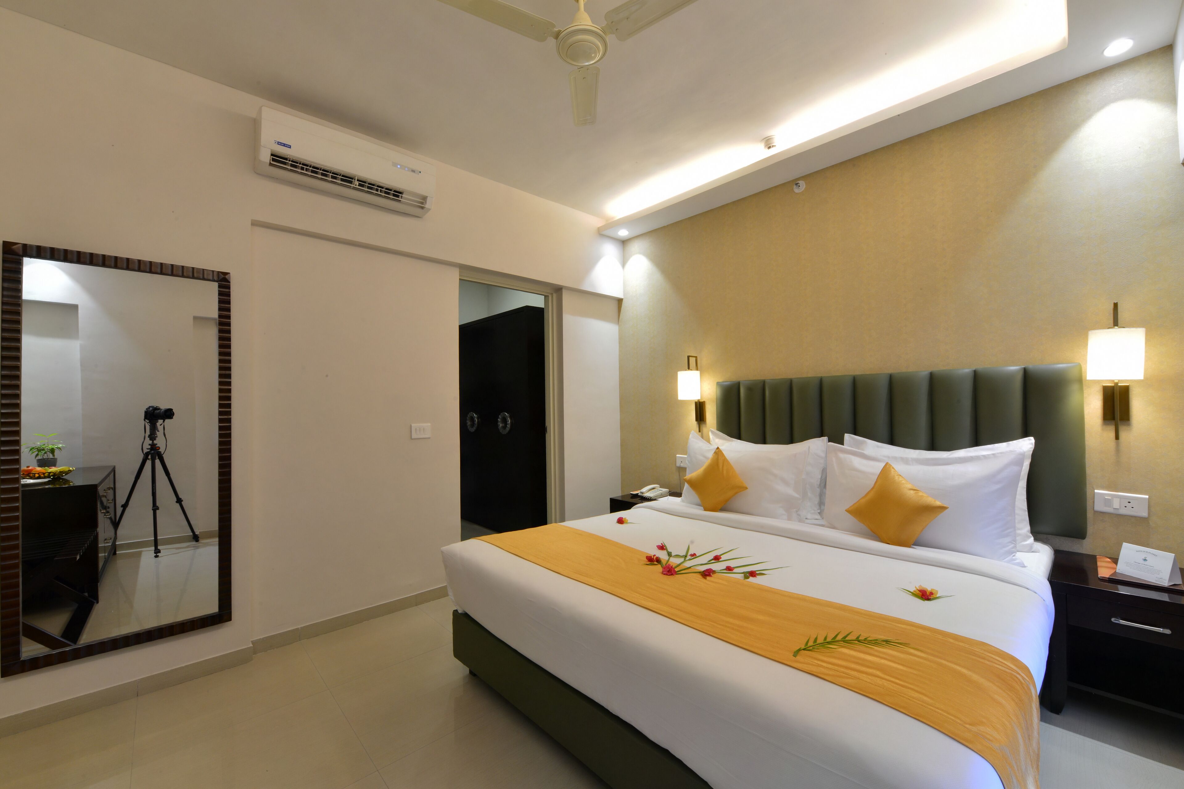 Ein Hotelzimmer mit Bett, Spiegel, Schreibtisch und Deckenventilator.