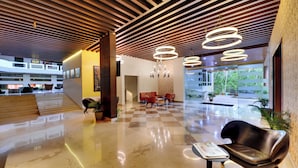 A modern lobby with a checkered floor, leather seating, and a staircase leading to upper levels. - The Fern Residency Pune, Vadgaon-Talegaon, Series by Marriott (Mawal)