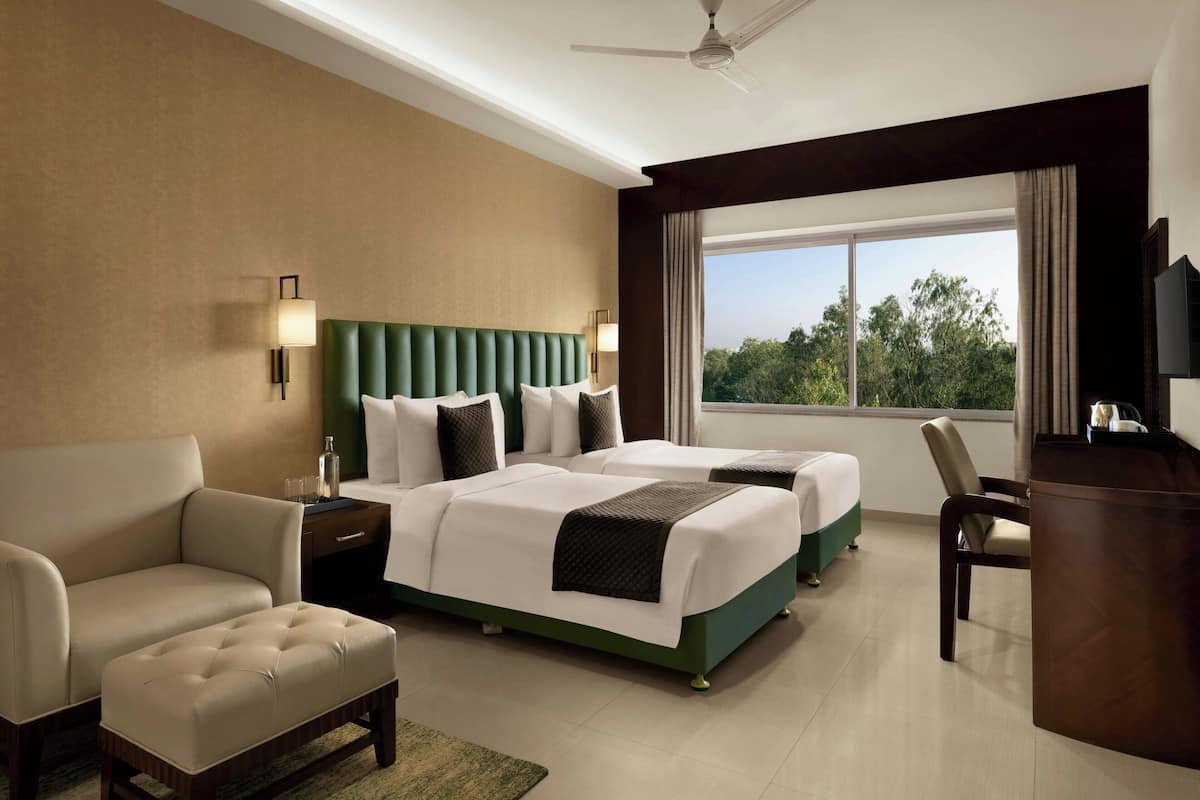 A hotel room with a bed, a sofa, a desk, and a TV.