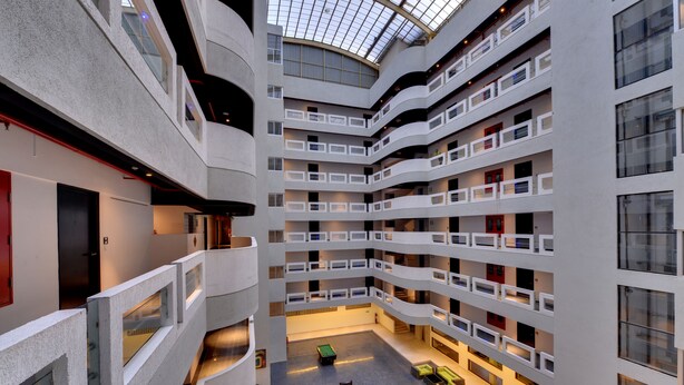 A multi-level atrium with a glass ceiling, multiple balconies, and a central open space with seating. - The Fern Residency Pune, Vadgaon-Talegaon, Series by Marriott (Mawal)