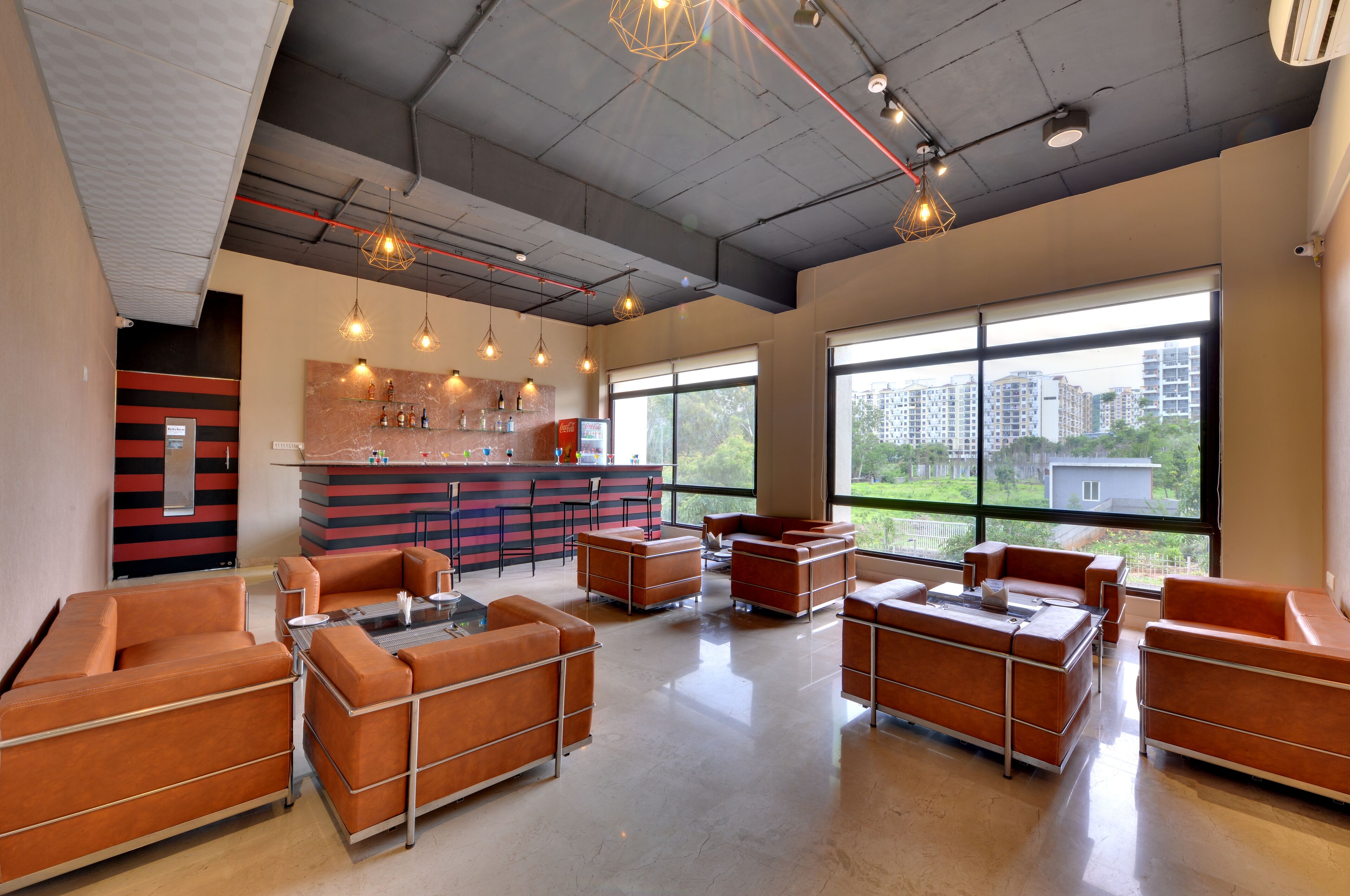A modern lounge area with leather sofas, a bar counter, and large windows offering a city view.
