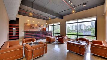 A modern lounge area with leather sofas, a bar counter, and large windows offering a city view.