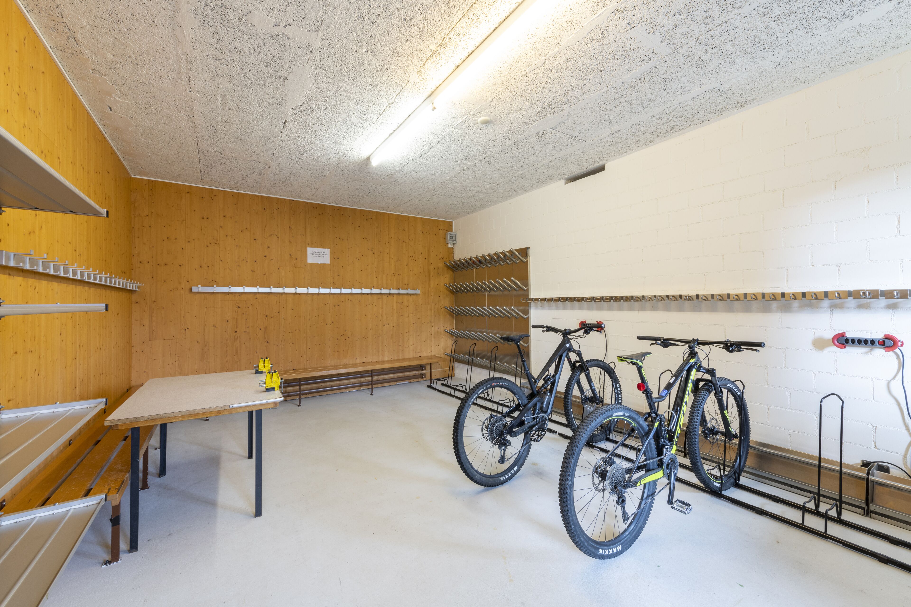 A clean, well-lit indoor space with wooden walls, a table, and bike racks.