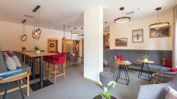 A modern hotel lobby with a dining area, seating arrangements, and artwork on the walls.