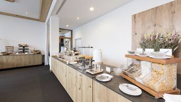 A buffet setup with a wooden counter, various food containers, and a decorative wall with flowers.