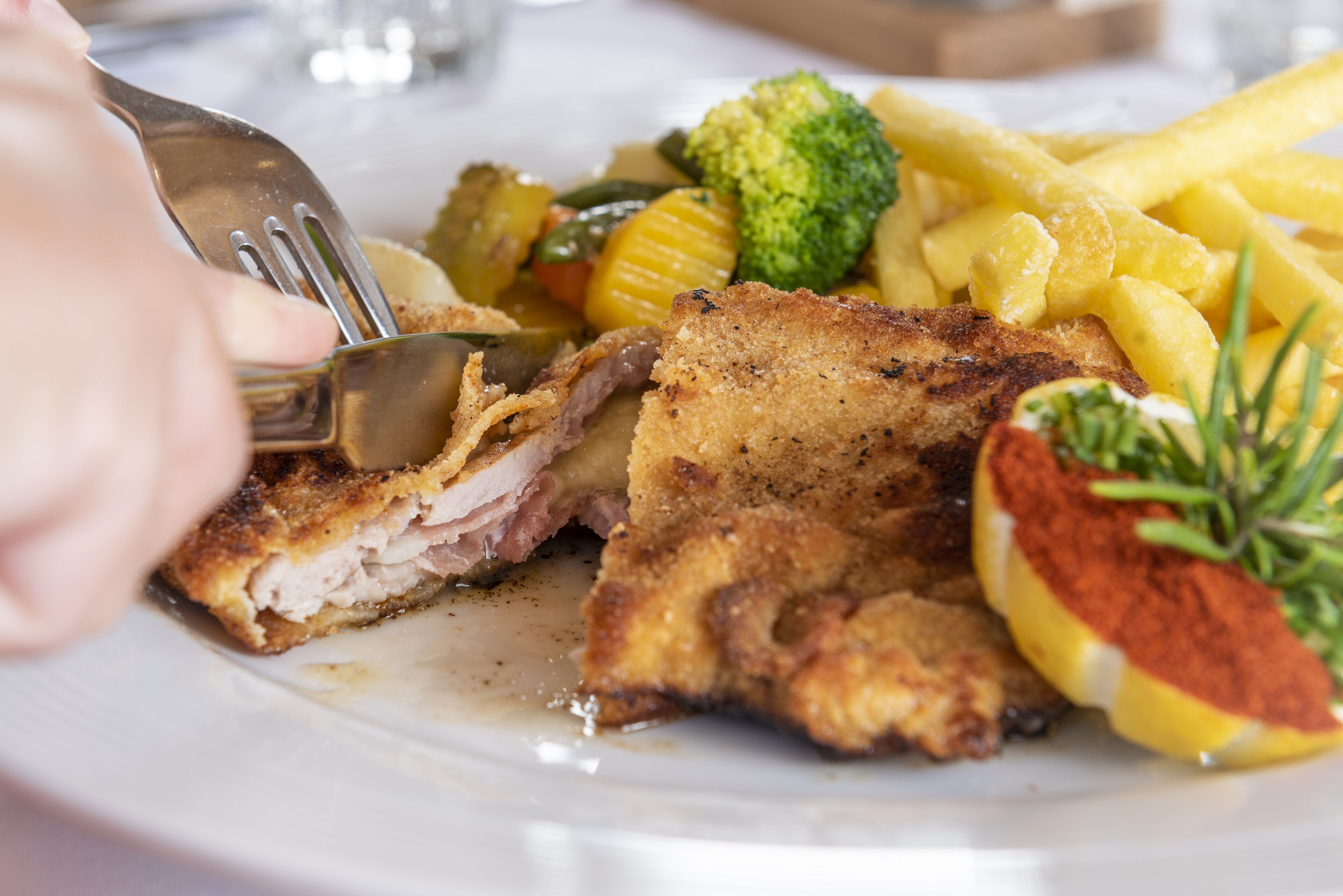 A plate with a piece of breaded meat, vegetables, and fries.