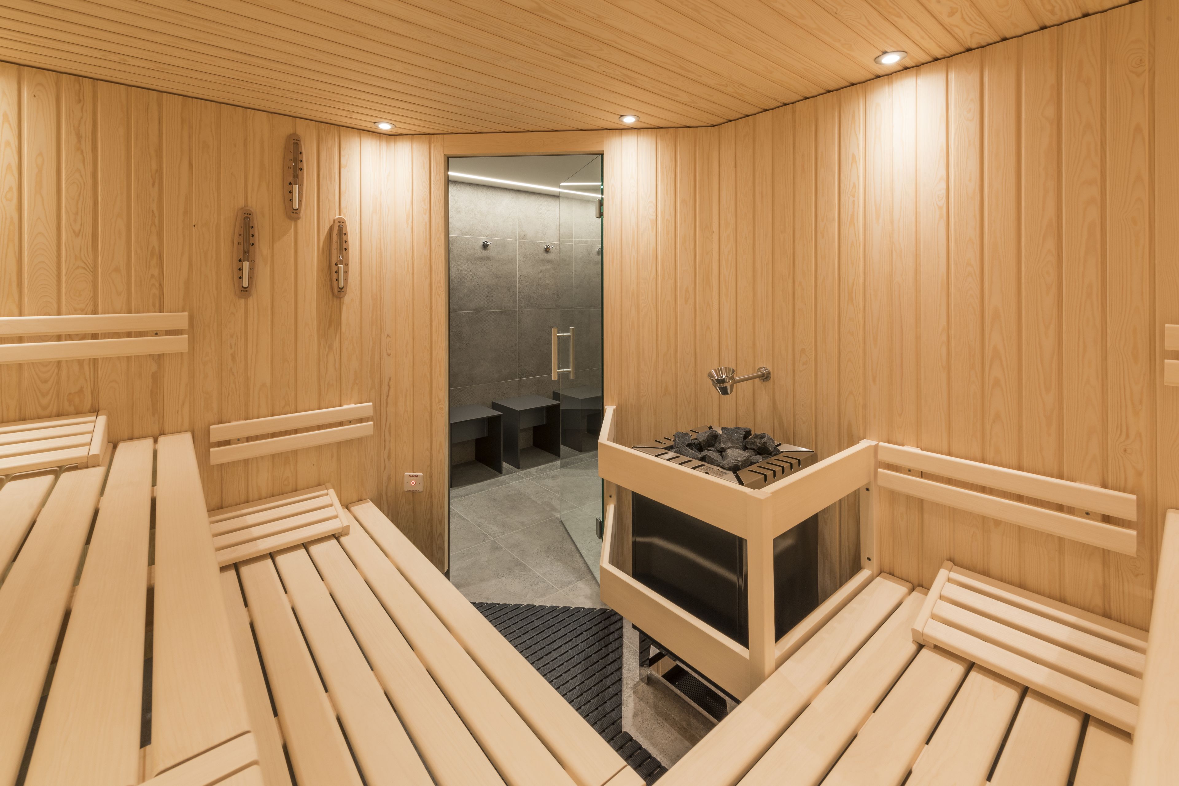 Een sauna met houten banken en een sauna-apparaat.