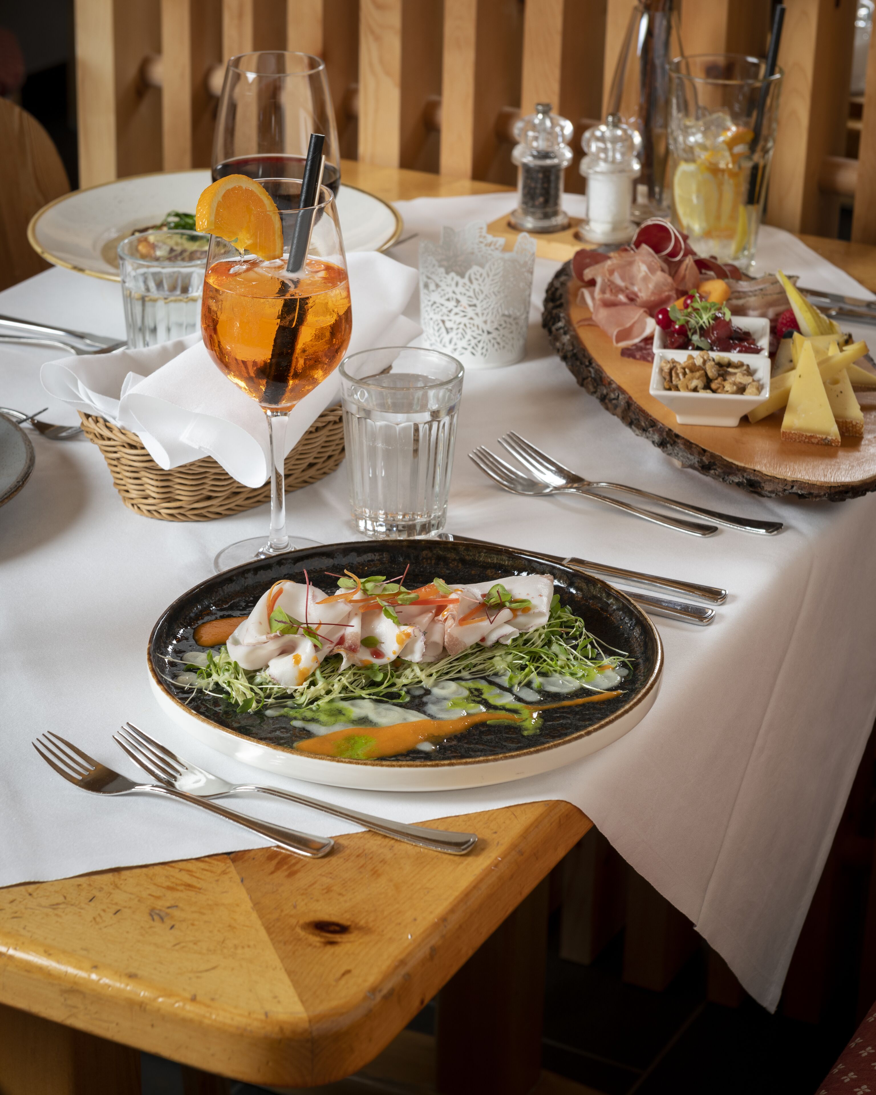 Una mesa de comedor dispuesta con platos, vasos y cubiertos.