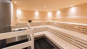 A sauna with wooden benches and a bench with a towel rack. - Hostel by Randolins (St. Moritz)