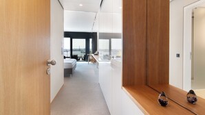 Une chambre d’hôtel moderne avec vue sur la ville, une porte en bois et une petite table agrémentée d’objets décoratifs.