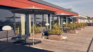 Une terrasse sur le toit, aménagée avec des espaces de détente en plein air, des jardinières et des parasols.