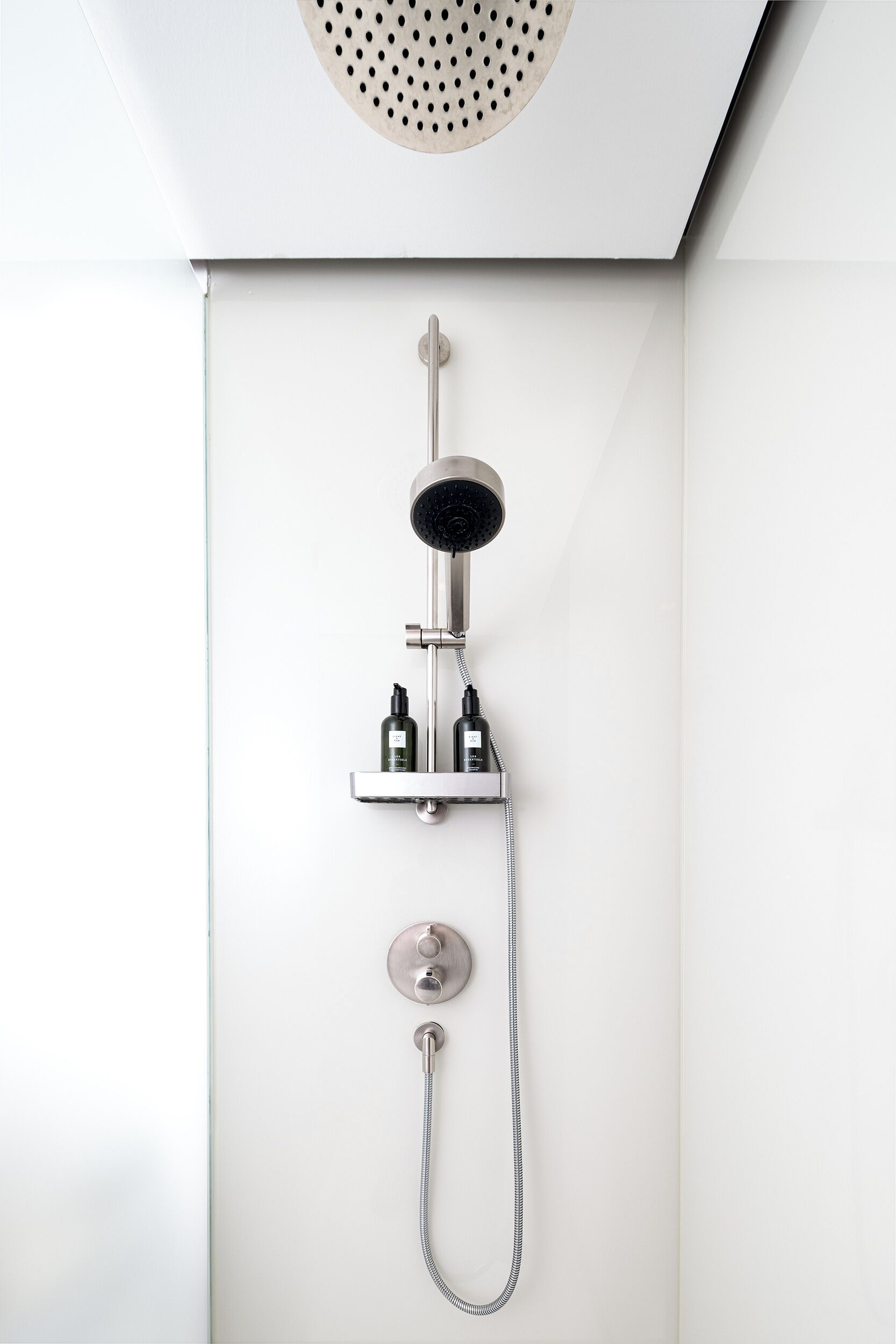 Eine moderne Dusche mit Handbrause, Duschkopf und Bedienfeld.