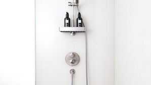 Une douche moderne dotée d’un pommeau de douche à main, d’un pommeau de douche fixe et d’un panneau de commande.