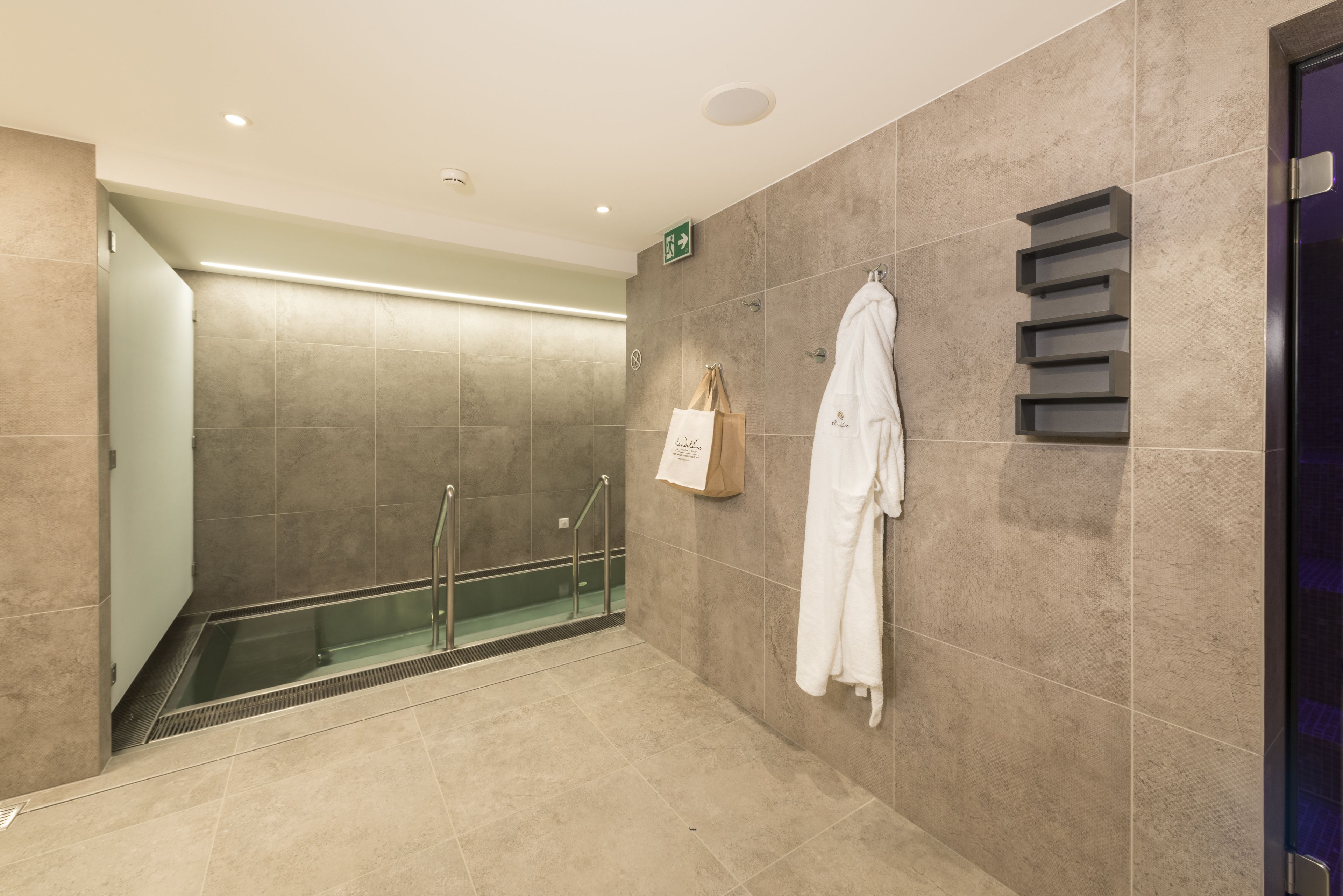 Ein modernes Badezimmer mit einer Duschkabine aus Glas, einem Handtuchhalter und einem an der Wand befestigten Regal.