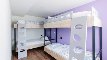 A bunk bed room with a purple wall, wooden flooring, and a white ceiling.