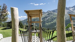 Un columpio de madera con vistas a montañas al fondo.