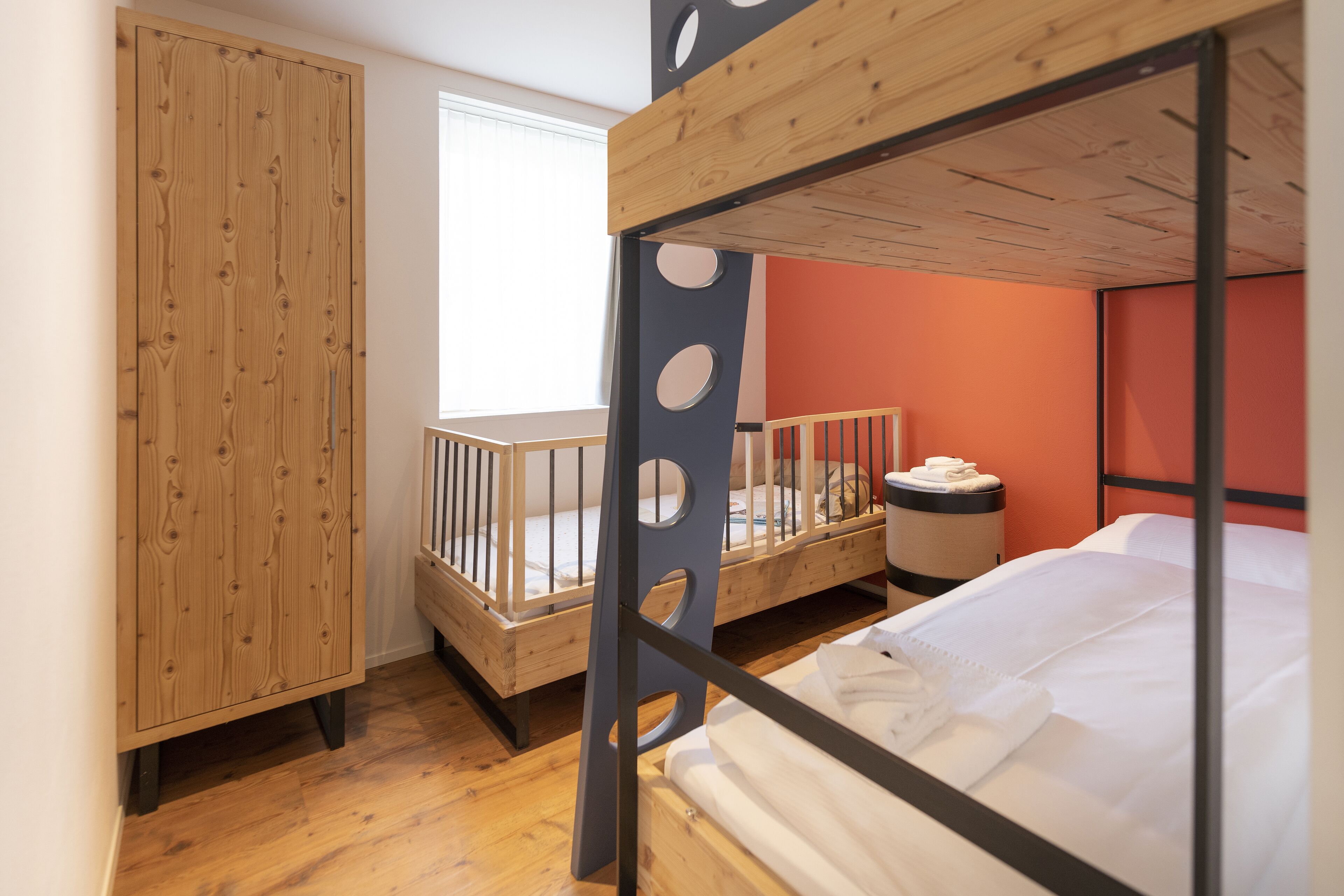 Ein Zimmer mit einem Etagenbett, einem Holzschrank und einem kleinen runden Tisch.