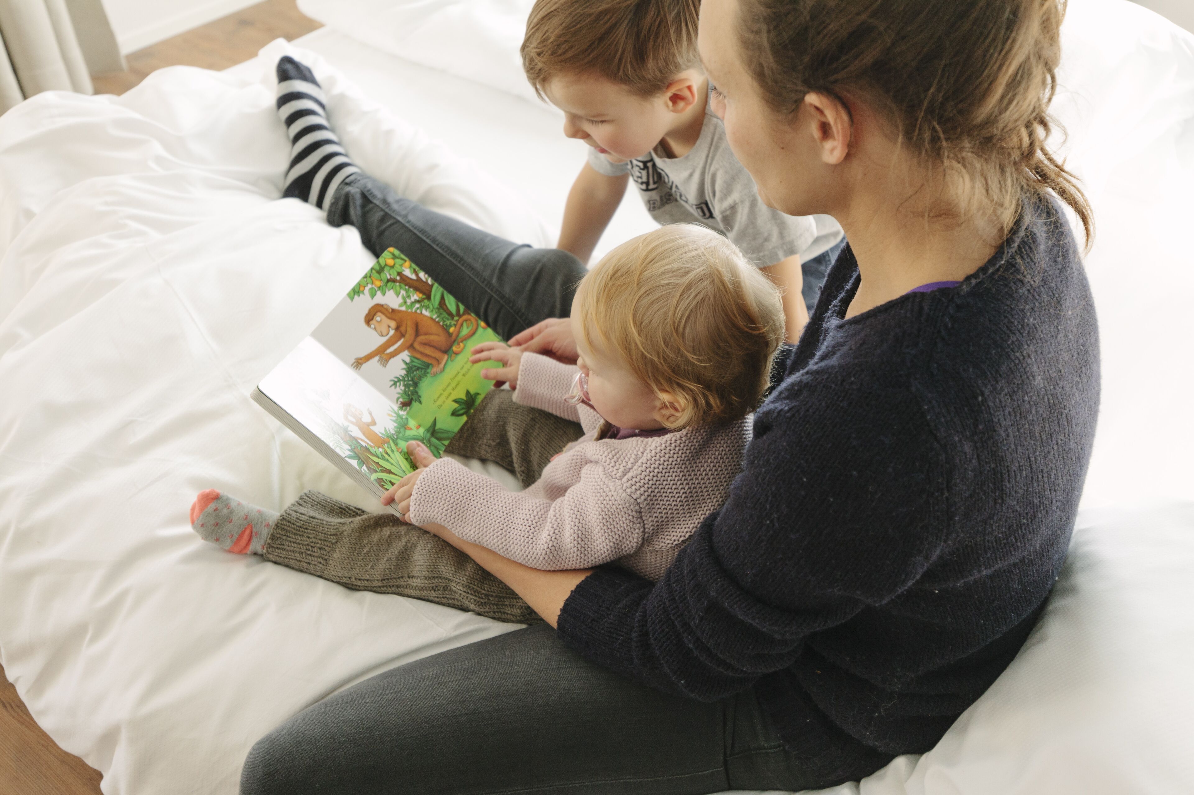 Una persona sentada en una cama con un libro.