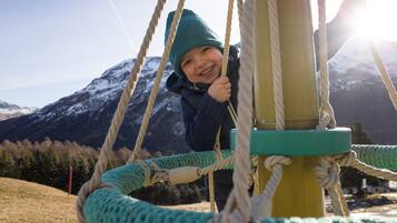 Un niño columpiándose en una cuerda, con montañas al fondo.