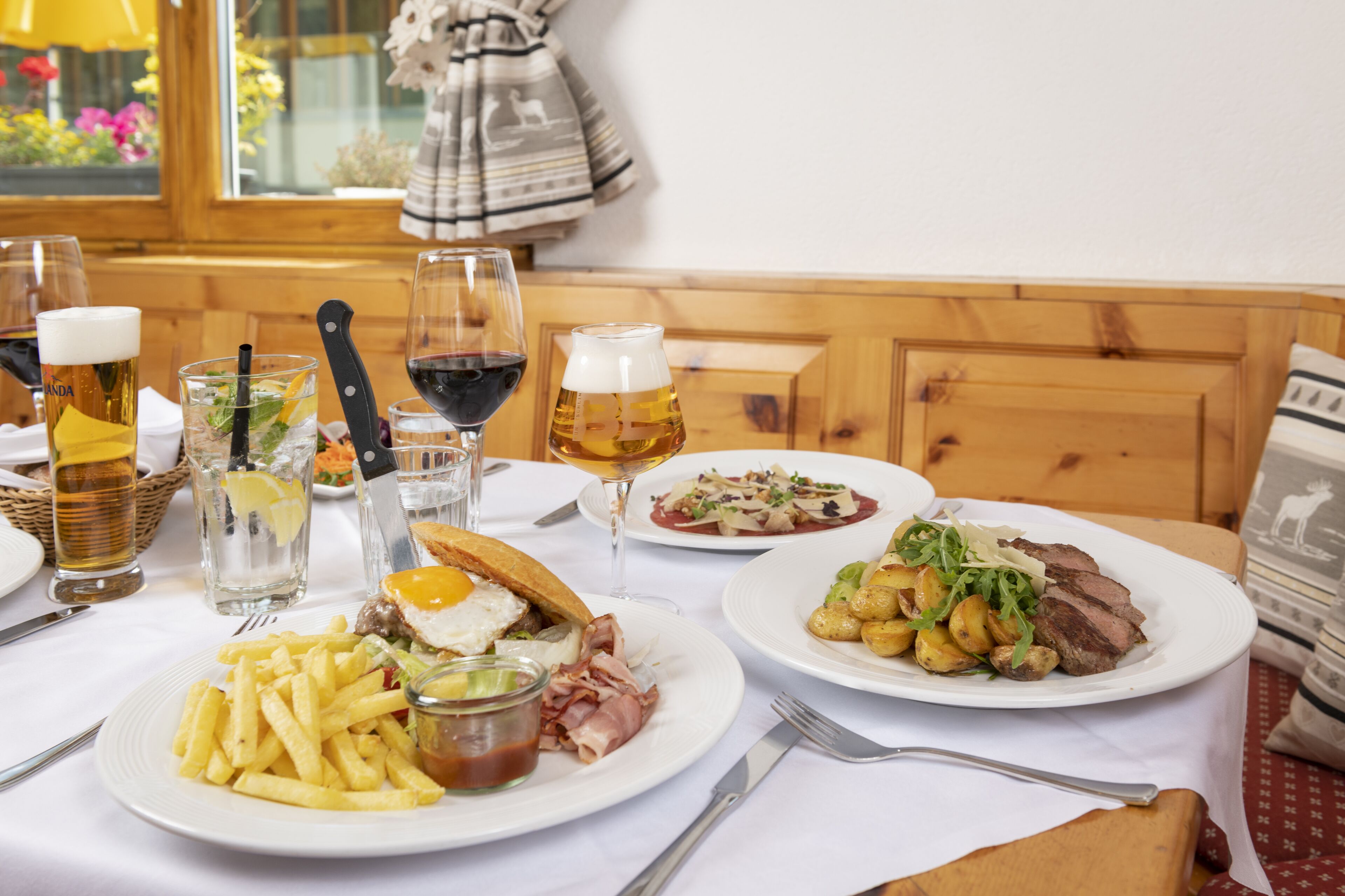 A dining table with various dishes, glasses of beer, and a knife.