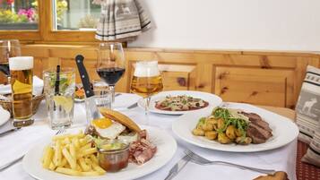 A dining table with various dishes, glasses of beer, and a knife.