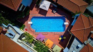 Eine Vogelperspektive auf einen Swimmingpool, umgeben von Gebäuden mit roten Ziegeldächern.