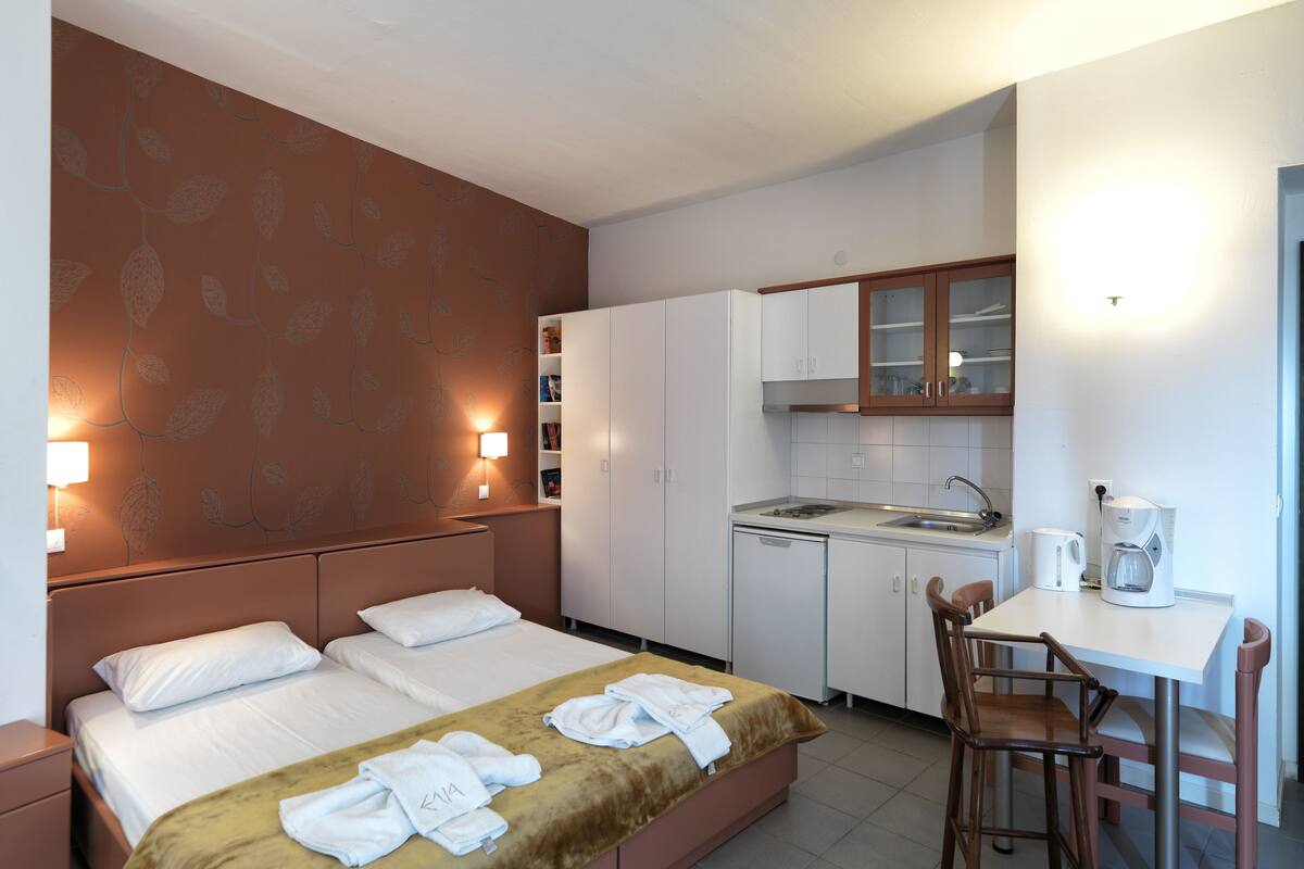 Ein Hotelzimmer mit Bett, einer kleinen Küchenzeile, einem Essbereich und einem Badezimmer.