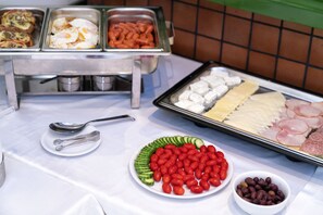 A buffet table with various food items including eggs, sausages, cheese, and vegetables.