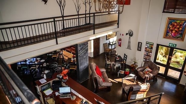 Um hall amplo com teto alto, escadaria e área de estar com poltronas de couro.