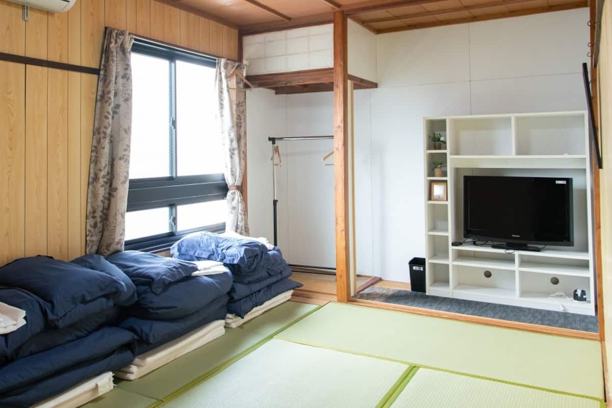 A room with a bed, a TV, and a shelf with items.