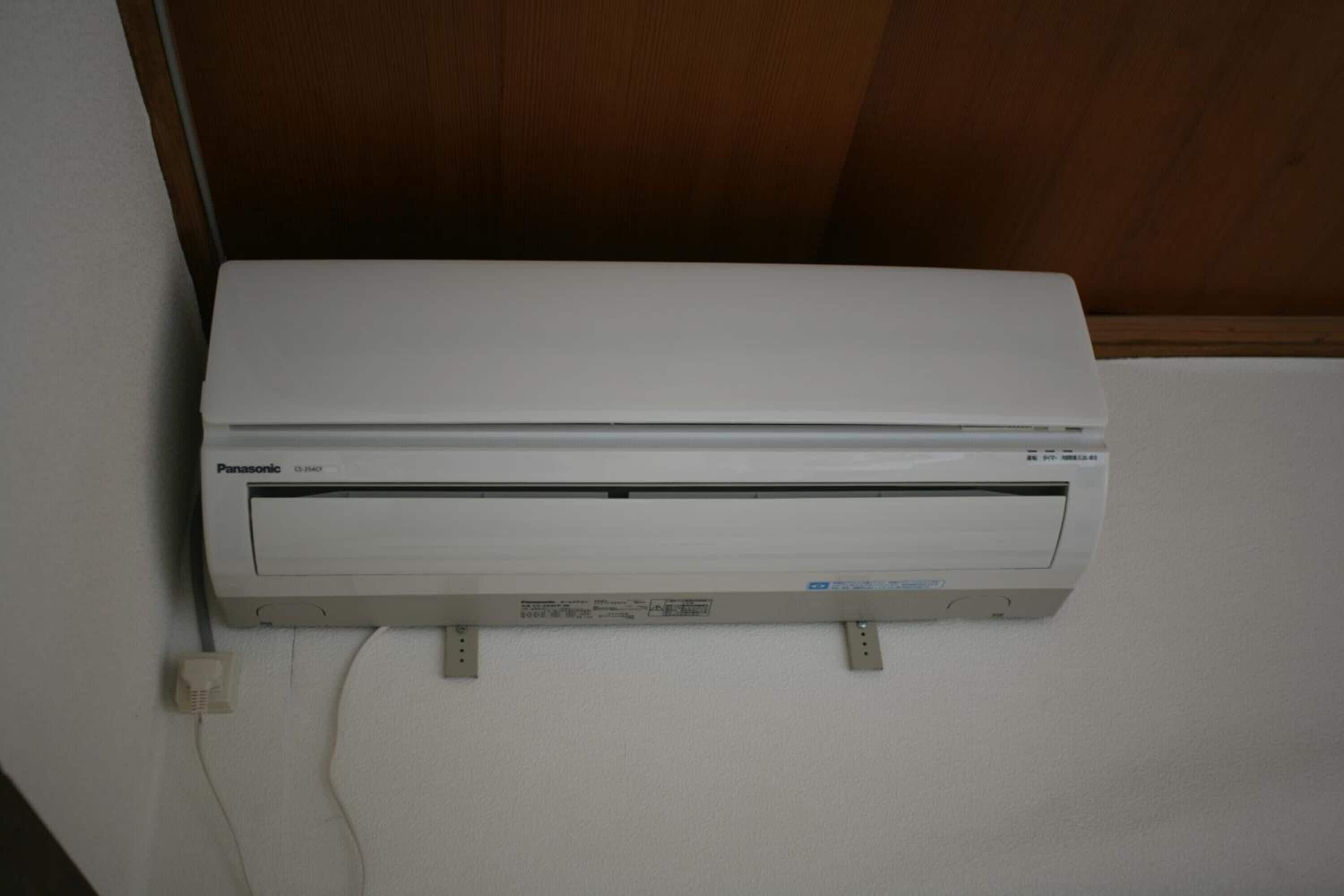 Een Panasonic airconditioner aan een muur bevestigd, met een stroomkabel aangesloten.