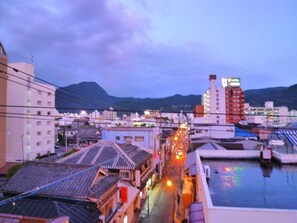 A traditional Japanese town with narrow streets, traditional buildings, and a modern hotel in the background. - Guesthouse Danran (Beppu)