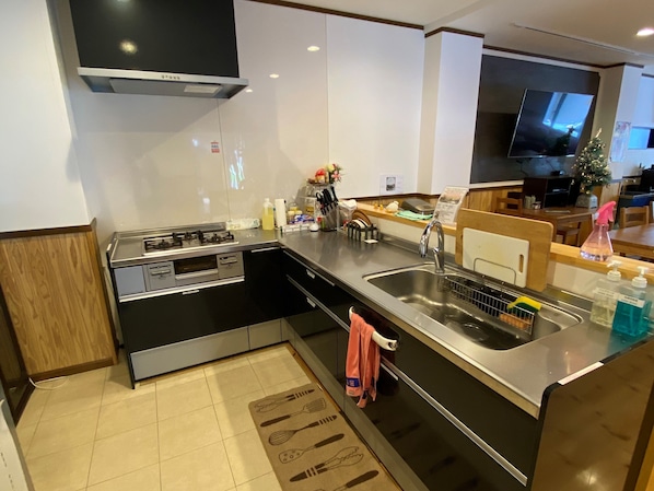 Una cocina moderna con estufa, pileta y un comedor con un árbol de Navidad.
