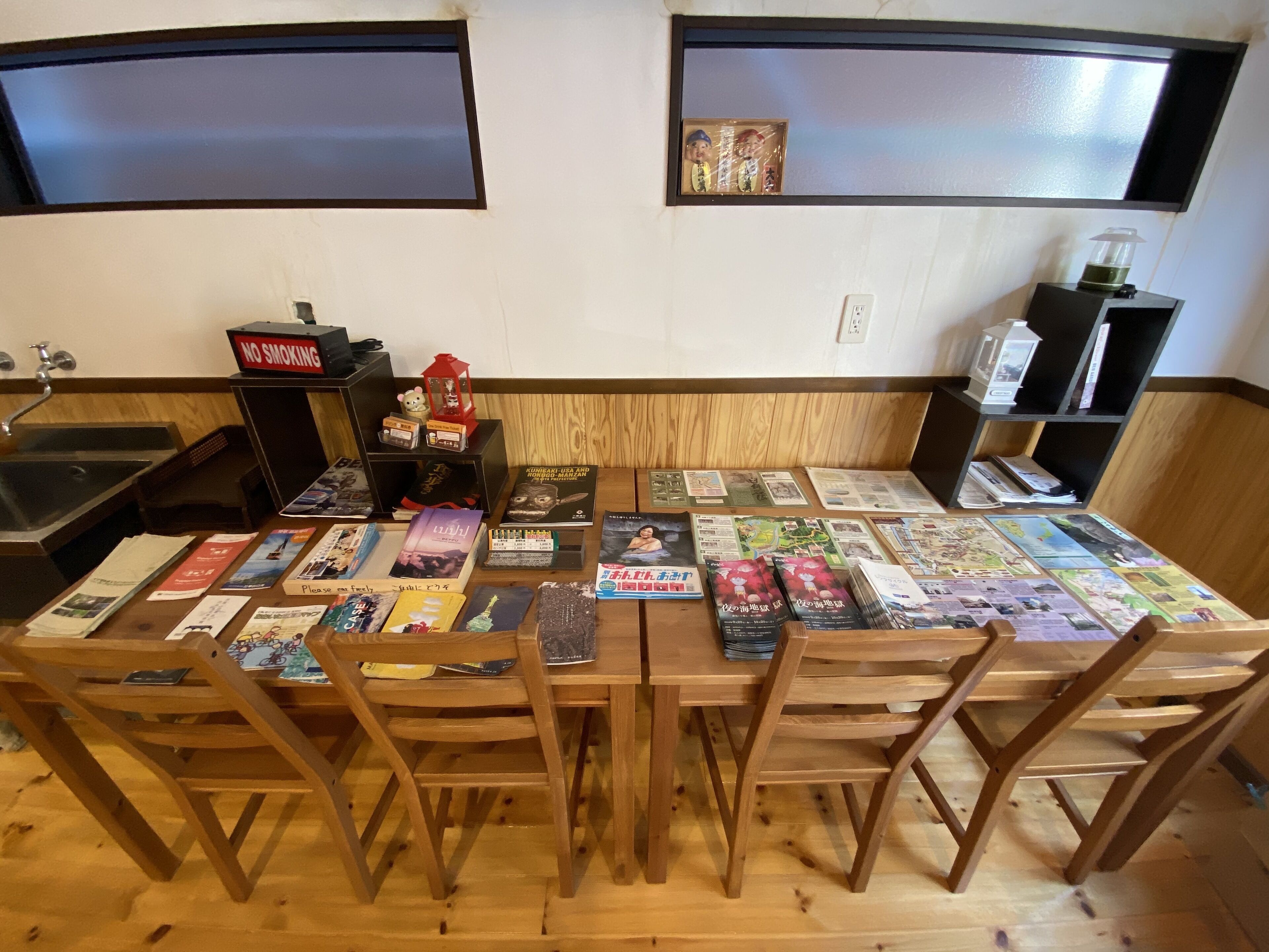 A wooden table with magazines and brochures, a 'No Smoking' sign, a small shelf with a clock, and a window with a reflection.