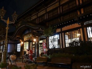 A traditional Japanese building with a wooden facade and large windows. There are bicycles parked outside and a bench in the foreground. - Guesthouse Danran (Beppu)