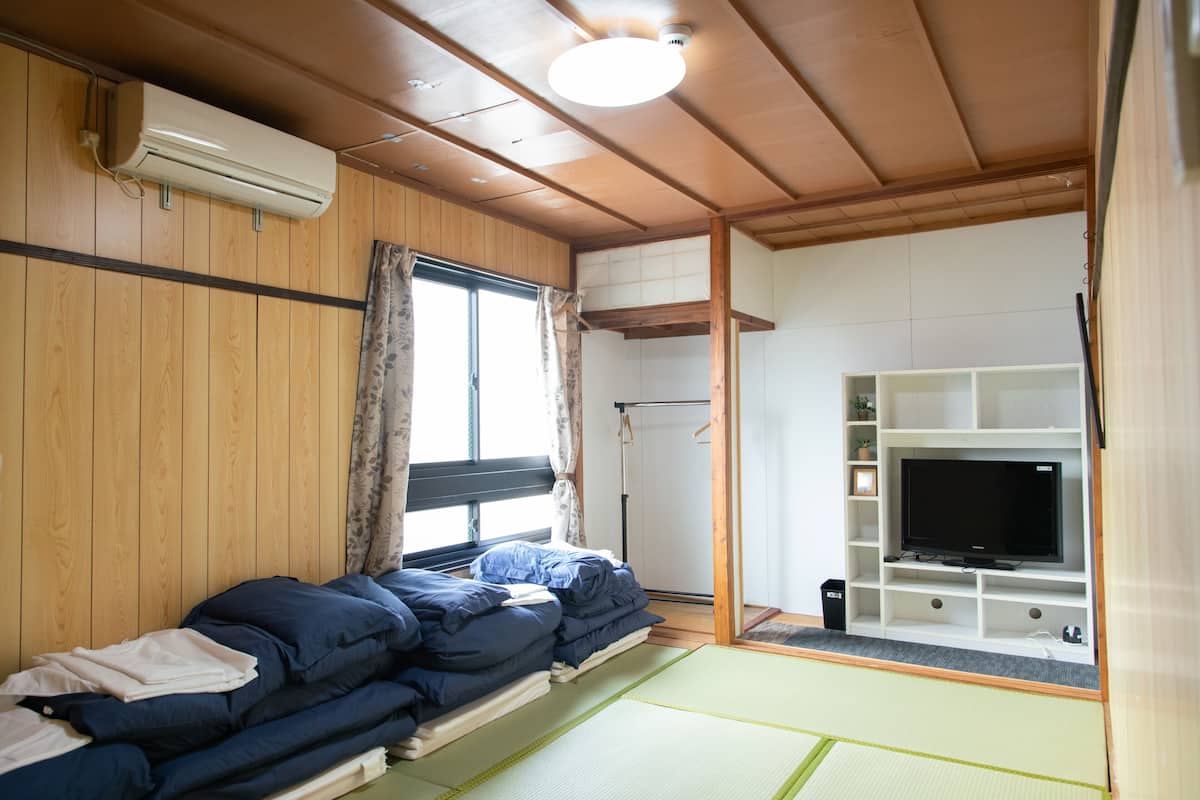 A room with a bed, a TV, and a wooden ceiling.