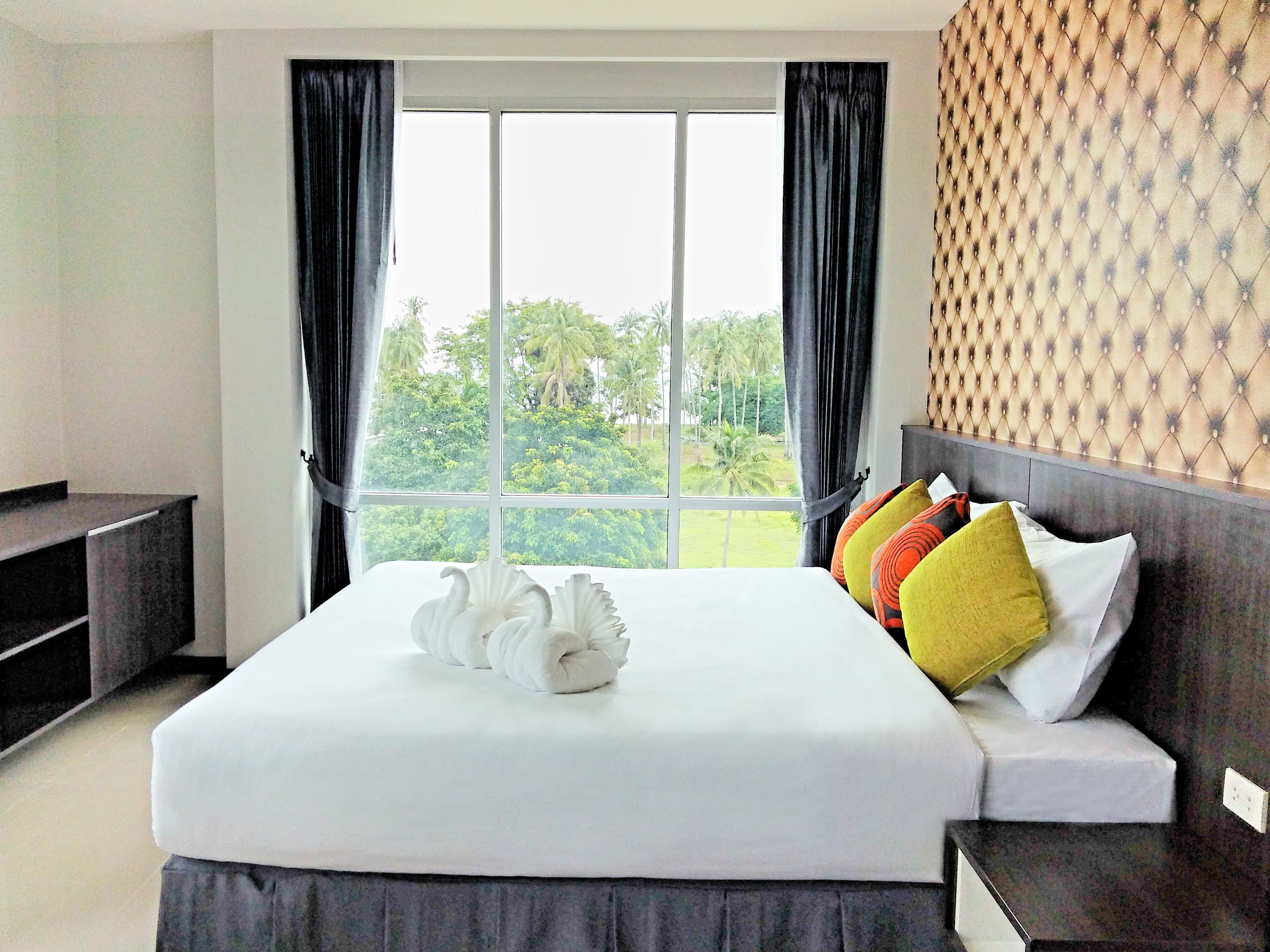 Habitación de hotel con una cama grande, un televisor y una ventana con cortinas.
