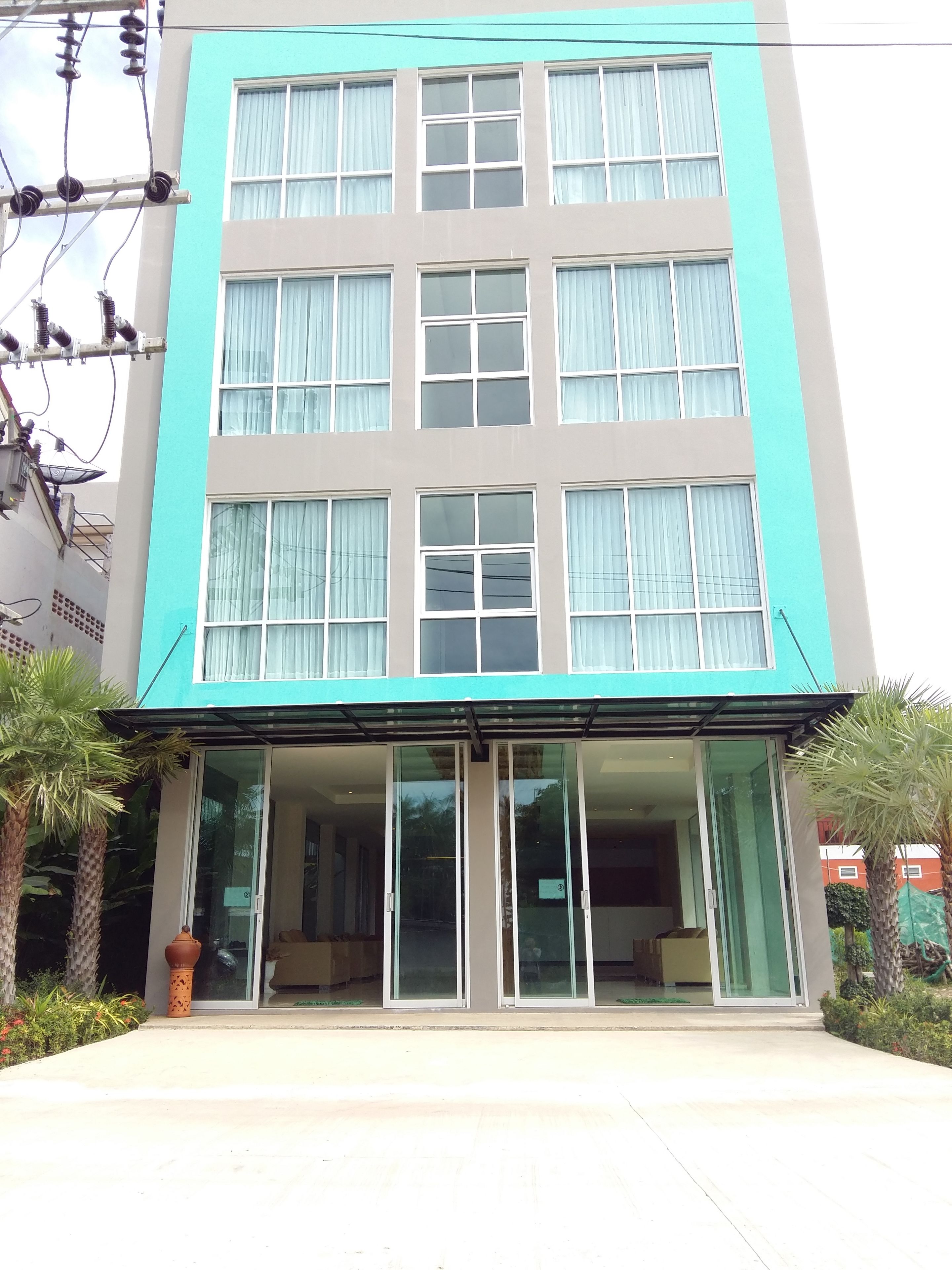 Un edificio de varios pisos con fachada plana, ventanas amplias y acceso de vidrio.