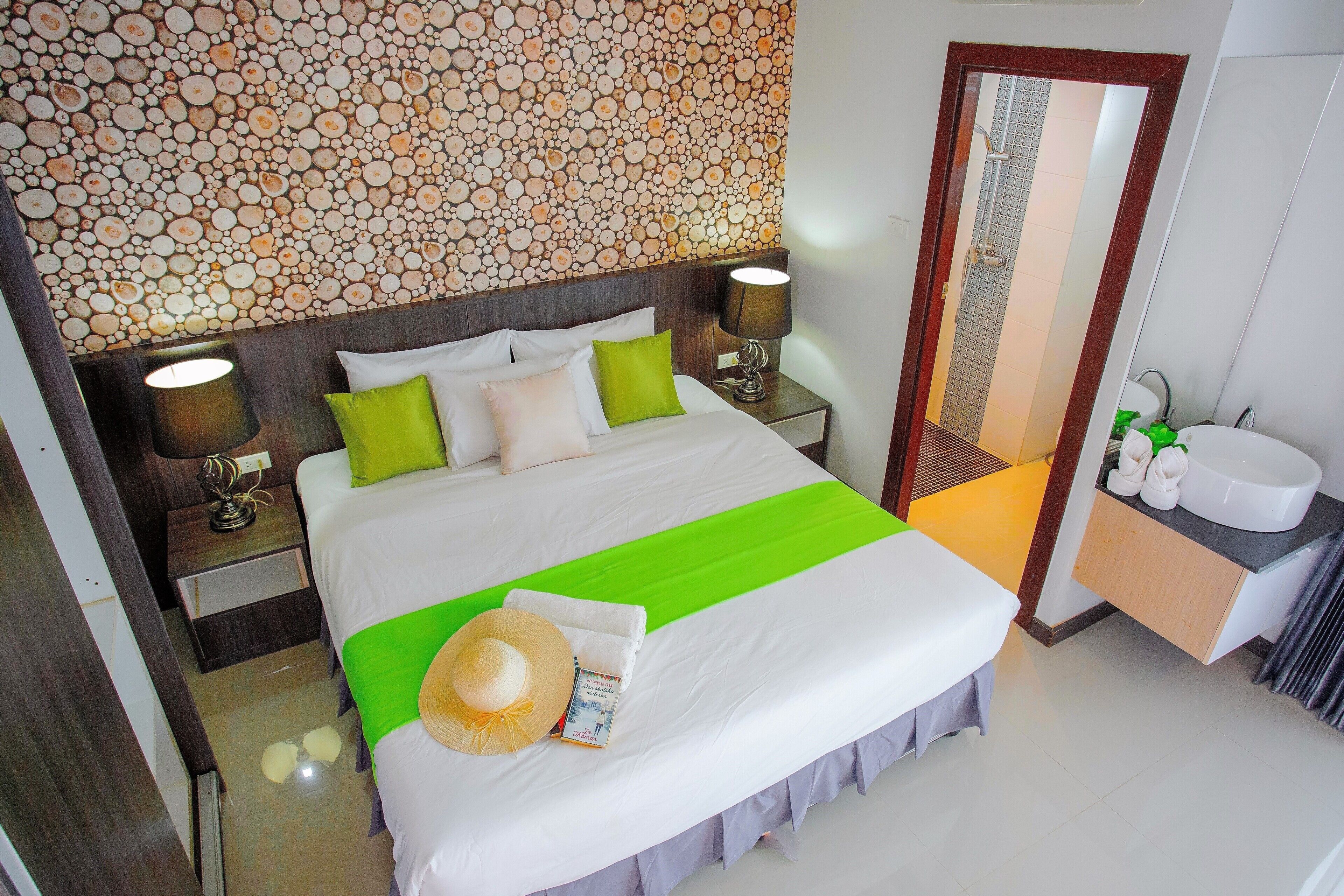 A hotel room with a neatly made bed, a bathroom with a sink and mirror, and a unique wall design.