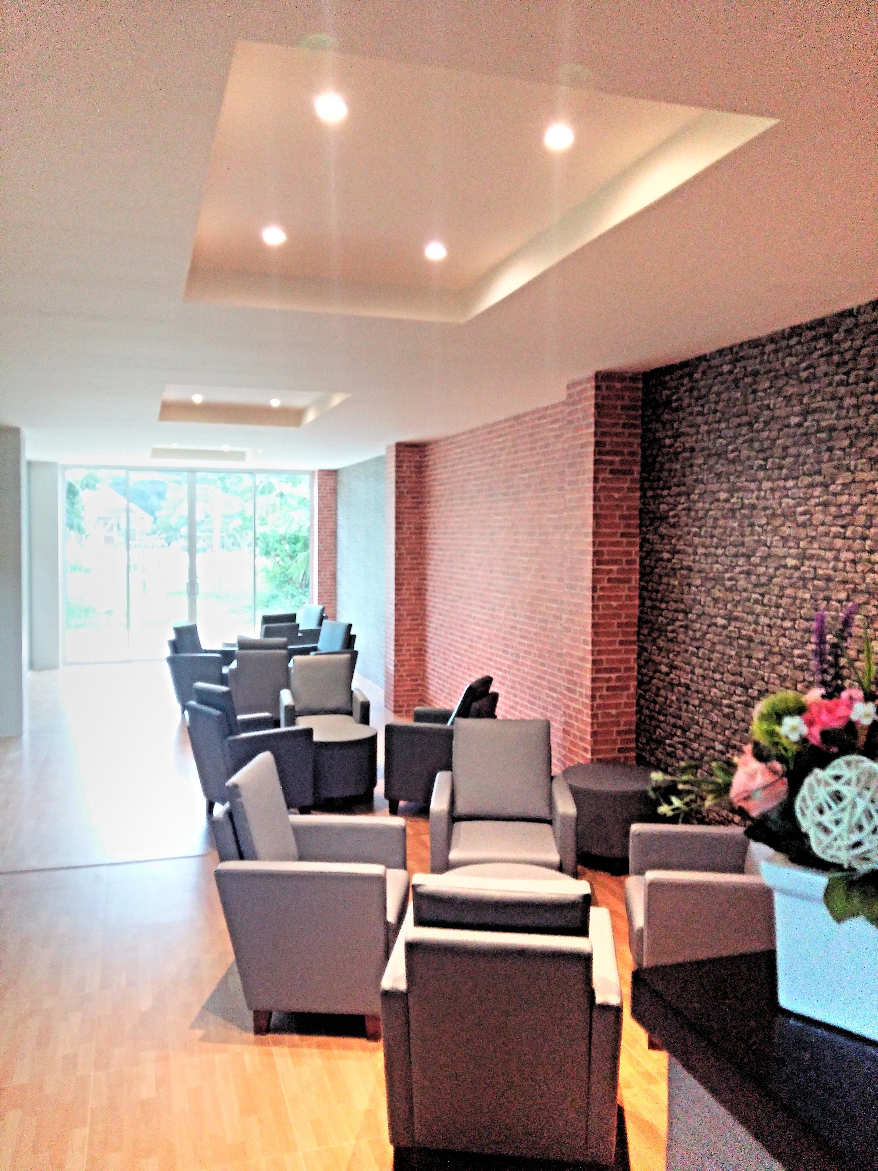A modern waiting area with multiple seating options, a brick accent wall, and a large window offering a view of the outdoors.