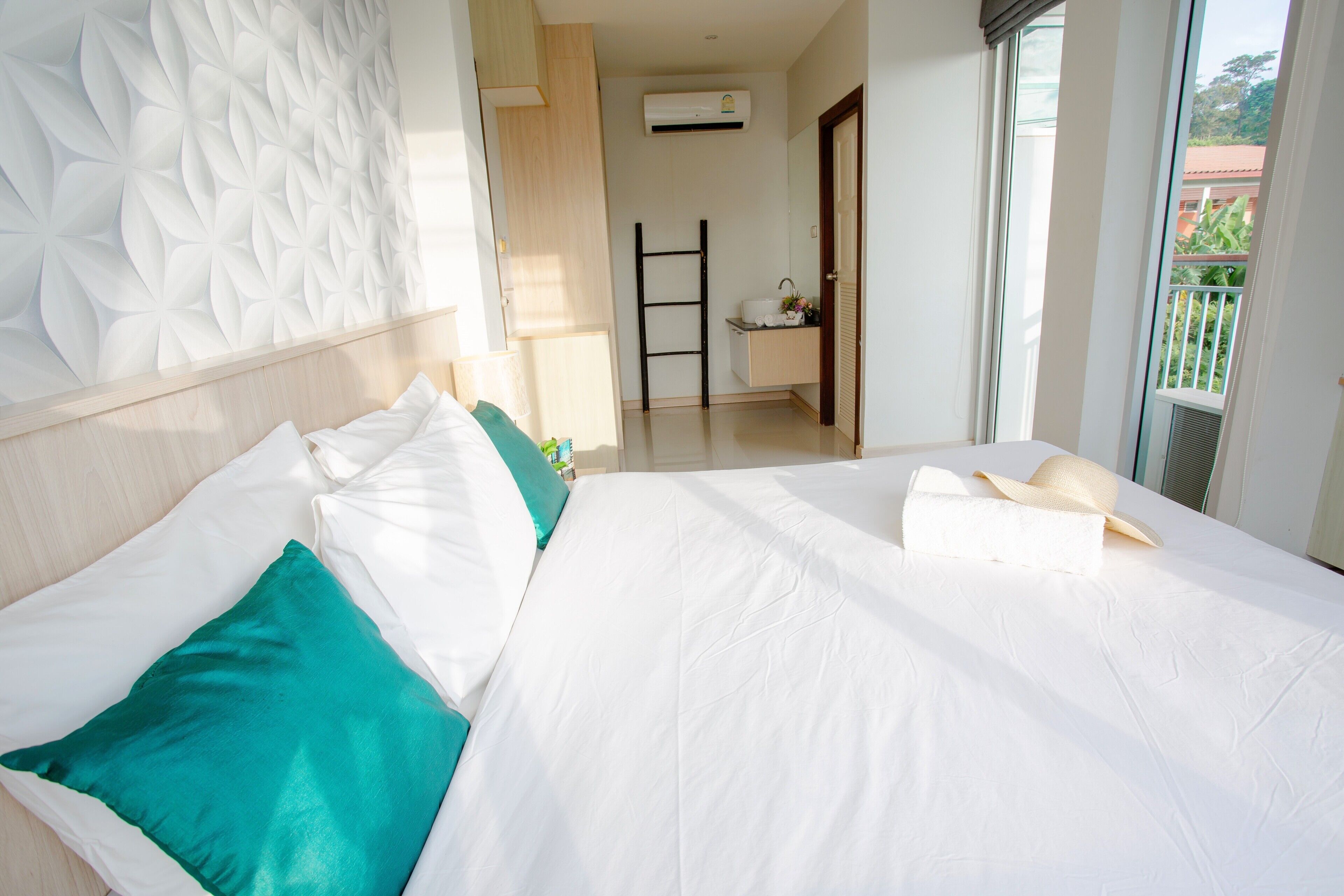 A hotel room with a bed, a headboard, a window, and a door.